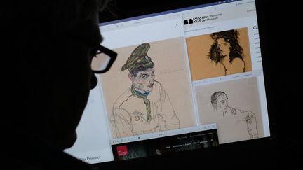 Cette photo, réalisée à Los Angeles (Etats-Unis) le 13 septembre 2023, montre une personne regardant sur un ordinateur plusieurs oeuvres de l'artiste autrichien Egon Schiele (1890-1918), dont "Portrait d'un homme" (1917) et "Fille aux cheveux noirs" (1911). (CHRIS DELMAS / AFP)