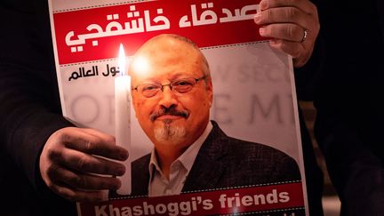 Un manifestant tient une affiche représentant le journaliste saoudien Jamal Khashoggi et une bougie allumée lors d'un rassemblement devant le consulat d'Arabie saoudite à Istanbul, le 25 octobre 2018. (YASIN AKGUL / AFP)