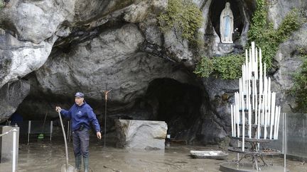 Un homme chasse la boue du Sanctuaire de Lourdes au lendemain d'une crue du Gave de Pau, le 21 octobre 2012.&nbsp; (CAROLINE BLUMBERG / REUTERS)