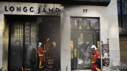 Des pompiers devant une boutique des Champs Elysées le 16 mars 2019. (JULIEN DE ROSA / EPA)