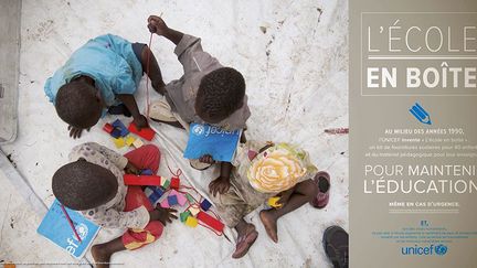 Des enfants congolais réfugiés découvrent, avec leur enseignant, un kit de fournitures scolaires.
 
 (UNICEF / Sibiloni)