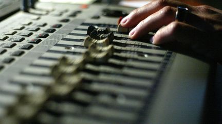 Un ingénieur du son travaille sur une table de mixage, dans un studio d'enregistrement (illustration). (MARTIN BUREAU / AFP)