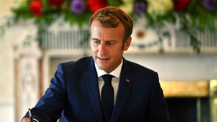 Emmanuel Macron signe un livre d'or lors de sa visite à Dublin, en Irlande, le 26 août 2021. (CLODAGH KILCOYNE / AFP)