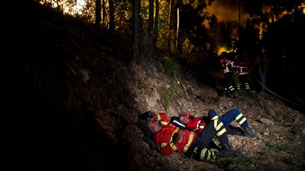 Des pompiers se reposent après avoir combattu les flammes à Penela (Portugal). (PATRICIA DE MELO MOREIRA / AFP)