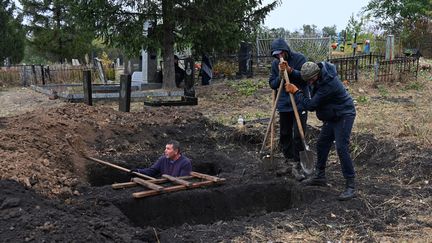 Des habitants creusent des tombes au cimetière du village de Hroza, dans la région de Kharkiv (Ukraine), le 7 octobre 2023. (SERGEY BOBOK / AFP)