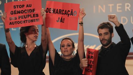 Même soirée, autre lutte. De nombreux artistes, dont les Brésiliennes Isabella Nader, productrice, Renee Nader Messora, réalisatrice et le réalisateur portuguais Joao Salaviza ont brandi des panneaux afin de dénoncer le massacre des peuples autochtones. 
 (VALERY HACHE / AFP)