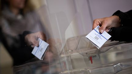 Un citoyen tend sa carte d'électeur. Photo d'illustration. (LOIC VENANCE / AFP)