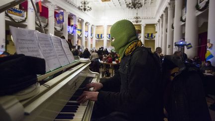 Un homme masqu&eacute; joue du piano lors d'une r&eacute;union de manifestants anti-gouvernementaux dans la mairie de Kiev (Ukraine), le 1er favrier 2014. (THOMAS PETER / REUTERS)