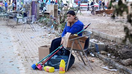 Une femme se repose à côté d'affaires de nettoyage à Sedavi, près de Valence, dans le sud-est de l'Espagne, le 5 novembre 2024. (JOSE JORDAN / AFP)