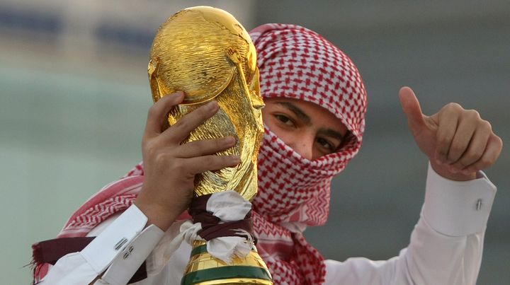 Un Qatari brandit une reproduction de la Coupe du monde de football, &agrave; Doha, le 3 d&eacute;cembre 2010. (MARWAN NAAMANI / AFP)