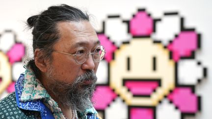 L'artiste Takashi Murakami se tient devant "Murakami. Flower Pink &amp; White, 2000" lors de l'avant-première de presse du 11 mai 2022 pour "An Arrow through History" aux galeries Gagosian de New York. (TIMOTHY A. CLARY / AFP)