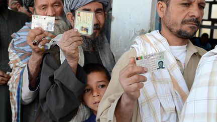 Des Afghans montrent leurs cartes d'identit&eacute; avant de voter pour le scrutin pr&eacute;sidentiel &agrave; Kandarah, le 5 avril 2014. (BANARAS KHAN / AFP)