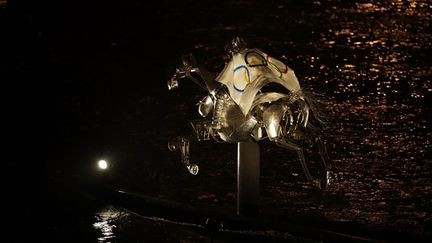 Une cavalière d'argent traverse la Seine, drapeau olympique sur les épaules, pour ce qui restera comme l'une des images marquantes de la cérémonie. (CLIVE BRUNSKILL / AFP)