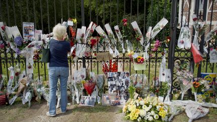 Une femme dépose des fleurs devant le portail d'entrée de la propriété La Brulerie d'Alain Delon à Douchy (Loiret), le 19 août 2024. (GUILLAUME SOUVANT / AFP)