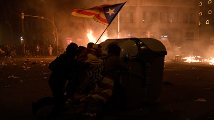 Des manifestants indépendantistes catalans derrière une poubelle, le 18 octobre 2019, à Barcelone (Espagne), lors d'affrontements avec la police. (JOSEP LAGO / AFP)