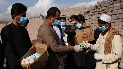 Une distribution de masques contre le coronavirus le 18 mars 2020 à Jalalabad, en Afghanistan, un des 25 pays qui recevra une aide du FMI pour faire face aux coûts de la lutte contre l'épidémie. (WALI SABAWOON / NURPHOTO / AFP)