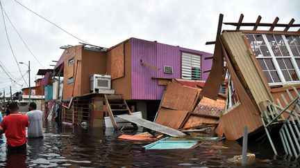 Des Portoricains marchent dans les rues inondées de Juana Matos, après le passage de l'ouragan Maria, le 21 septembre 2017. (HECTOR RETAMAL / AFP)