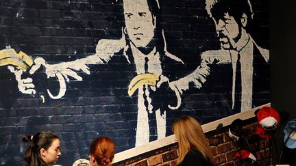 Des visiteuses devant "Pulp Fiction With Bananas Instead of Guns" de Banksy à l'exposition à l'Ifema de Madrid, le 6 décembre 2018.
 (Paolo Aguilar/EFE/Newscom/MaxPPP)