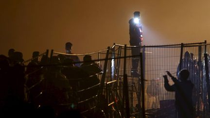 &nbsp; (Un policier autrichien à la frontière avec la Slovénie, à Sentilj, alors que des migrants attendent pour passer © REUTERS - Srdjan Zivulovic)