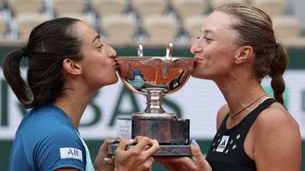 Caroline Garcia (à gauche) et Kristina Mladenovic embrassent la coupe à l'issue de leur victoire, le 5 juin 2022, à Roland-Garros dans le tournoi du double femmes. (THOMAS SAMSON / AFP)