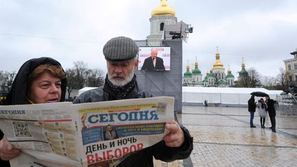 A Kiev (Ukraine), un couple lit un journal qui revient sur le vote du 28 octobre 2012&nbsp;pour les l&eacute;gislatives. (VIKTOR DRACHEV / AFP)