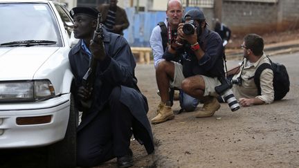 Un policier et des photographes se prot&egrave;gent apr&egrave;s avoir entendu des coups de feu pr&egrave;s du centre commercial Westgate &agrave; Nairobi (Kenya), le 23 septembre 2013. (REUTERS)