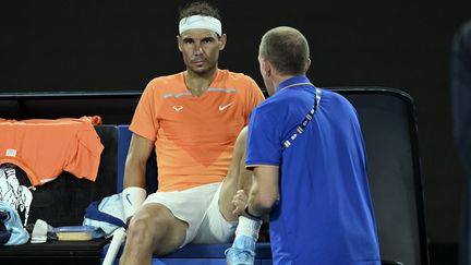 L'Espagnol Rafael Nadal manipulé par le kiné pour une blessure à la hanche, avant sa défaite lors du 2e tour de l'Open d'Australie, le 18 janvier 2023. (MANAN VATSYAYANA / AFP)