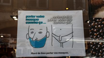 Une affichette rappelant les consignes sanitaires avec humour sur la vitre d'un magasin à Thionville (Moselle). Photo d'illustration. (PIERRE HECKLER / MAXPPP)