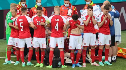 Les Danois réunis autour de leur capitaine Christian Eriksen, victime d'un arrêt cardiaque en plein match, lors de Danemark-Finlande, samedi 12 juin 2021. Un énorme choc pour tous les supporters de football dès la deuxième journée de l'Euro.&nbsp; (WOLFGANG RATTAY / AFP)