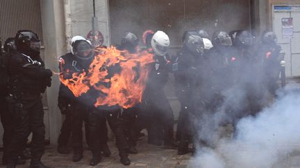 Un engin incendiaire explose devant des policiers lors de la manifestation contre la proposition de loi sur la "sécurité globale", à Paris, le 5 décembre 2020. (ANNE-CHRISTINE POUJOULAT / AFP)