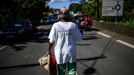 Une femme&nbsp;marche près d'un barrage routier à Sainte-Rose, en Guadeloupe, le 29 novembre 2021. (CHRISTOPHE ARCHAMBAULT / AFP)