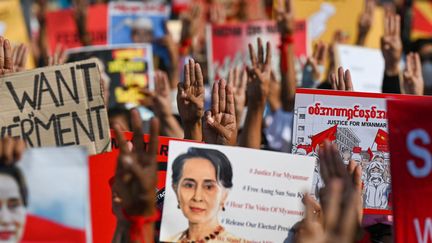 Des manifestants brandissent des pancartes en soutien à&nbsp;l'ex-dirigeante birmane Aung San Suu Kyi, écartée du pouvoir par un coup d'Etat de la junte militaire, le 16 février 2021 à Rangoun.&nbsp; (YE AUNG THU / AFP)