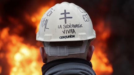 Un employer du site&nbsp;ArcelorMittal de Florange (Moselle) devant des pneus br&ucirc;l&eacute;s, le 8 mars 2012. (VINCENT KESSLER / REUTERS)