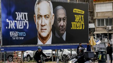 Une affiche représentant Benny Gantz (à gauche) et Benyamin Nétanyahou à Tel Aviv (Israël), lors de la campagne pour les élections législatives, le 1er mars 2020.&nbsp; (MENAHEM KAHANA / AFP)