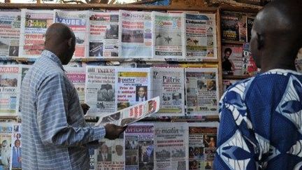 Les unes des journaux captent l'attention de ces deux passants dans la capitale malienne, Balmako. (AFP PHOTO / ISSOUF SANOGO )