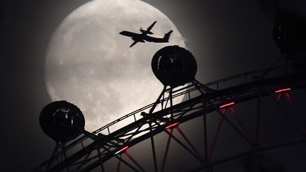 Un avion est photographié au desus du manège "London Eye" à Londres (Angleterre), la veille de la "super Lune", le 13 novembre 2016.  (TOBY MELVILLE / REUTERS)