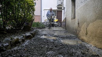 Un habitant de Saint-Romain-en-Gier (Rhône) nettoie les boues dans son jardin après de fortes pluies, le 25 octobre 2024. (MAXIME JEGAT / MAXPPP)