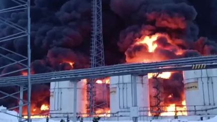 Une image tirée d'une vidéo diffusée par le ministère russe des Urgences, le 19 janvier 2024, montrant des sauveteurs travaillant pour éteindre un incendie dans un dépôt pétrolier à la suite d'une attaque de drone à Klintsy, dans la région de Briansk (Russie). (MINISTERE DES SITUATIONS D'URGENCE RUSSE / AFP)