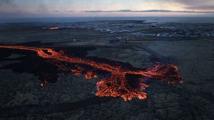 Une coulée de lave freinée par une barrière de protection, le 14 janvier 2024 à Grindavik (Islande). (HALLDOR KOLBEINS / AFP)