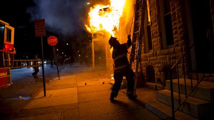 Un pompier intervient sur un incendie &agrave; Baltimore (Etats-Unis), le 28 avril 2015, alors que la ville est secou&eacute;e par des &eacute;meutes. (ERIC THAYER / REUTERS)