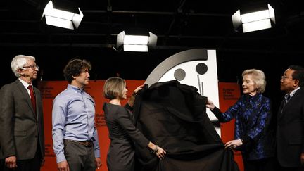 Des membres du "Bulletin of the Atomic Scientists" déplacent l'aiguille des minutes de l'horloge de l'apocalypse lors d'une conférence de presse à Washington, le 24 janvier 2023. (ANNA MONEYMAKER / GETTY IMAGES NORTH AMERICA / AFP)