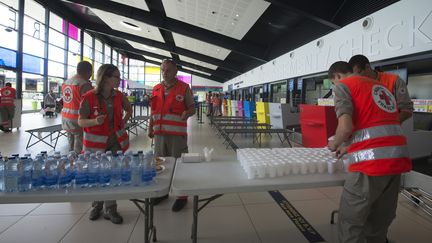 Des membres de la Croix-Rouge préparent des boissons pour les familles évacuées de Saint-Martin, le 9 septembre 2017, à l'aéroport de Pointe-à-Pitre, en Guadeloupe. (HELENE VALENZUELA / AFP)