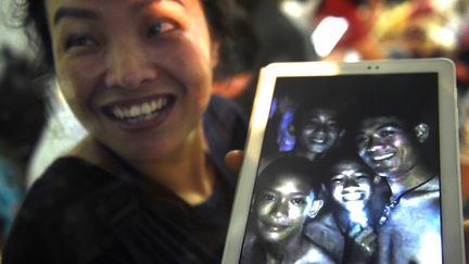 Une mère de famille montre les premières images des&nbsp;12 enfants et de leur entraîneur de football,&nbsp;retrouvés vivants après neuf jours passés dans une grotte du nord de la Thaïlande, le 2 juillet 2018.&nbsp; (LILLIAN SUWANRUMPHA / AFP)