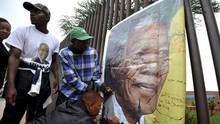 Des Sud-Africains &eacute;crivent des messages d'adieu &agrave; Nelson Mandela dans le quartier de&nbsp;Soweto, a Johannesbourg (Afrique du Sud), o&ugrave; l'ancien pr&eacute;sident a v&eacute;cu dans sa jeunesse, le 6 d&eacute;cembre 2013. (REUTERS)