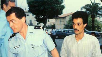 Omar Raddad (à droite) escorté par un gendarme lors de son arrestation pour le meurtre de Ghislaine Marchal, à Mougins (Alpes-Maritimes), le 26 juin 1991.&nbsp; (SCONAMIGLIO / MAXPPP)