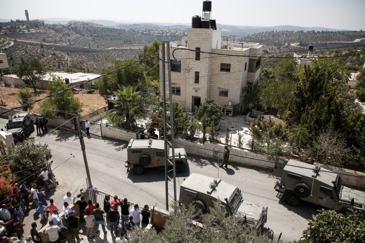 Des véhicules militaires et des soldats israéliens sont déployés à&nbsp;Beit Surik, village palestinien situé en face de la colonie où s'est déroulée l'attaque. Ils encerclent l'habitation d'un Palestinien. (ABBAS MOMANI / AFP)