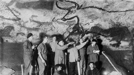 Le paléontologue et préhistorien français Henri Breuil observe le panneau des aurochs dans la salle des taureaux de la grotte de Lascaux en 1948 à&nbsp;Montignac en Dordogne, en compagnie d'autres archéologues et de deux des adolescents qui ont découvert la grotte Marcel Ravidat (D, assis) et Jacques Marsal (G, assis).&nbsp; (AFP)