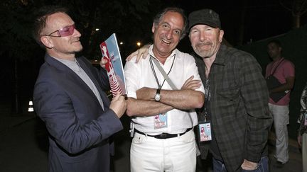 Le chanteur de U2, Bono (à gauche) et le guitariste The Edge (à droite) aux côtés de Gérard Drouot, directeur du Nice Jazz Festival, après le concert de Leonard Cohen. (BEBERT BRUNO/SIPA)