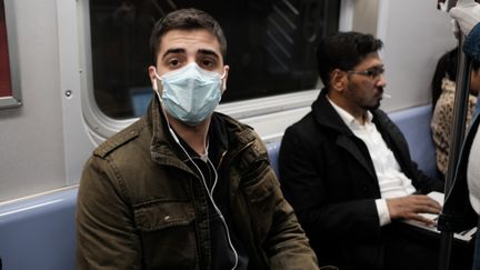 Un homme porte un masque médical dans le métro de New York alors que les Etats-Unis sont confrontés à l'épidémie de coronavirus, le 11 mars 2020. (SPENCER PLATT / AFP)