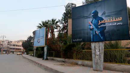  (Le long d'une rue de Raqqa, en Syrie, une affiche de Daech avec ce slogan : "Nous vaincrons en dépit de la coalition globale" (octobre 2014) © REUTERS/Nour Forat)